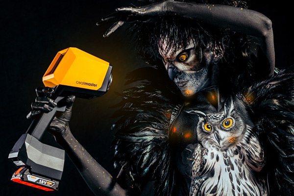 Bodypainting-Kunstwerk einer düsteren Figur mit leuchtenden Augen, Eulenmotiv auf der Brust und einem gelben Messgerät in der Hand (Coatmaster).