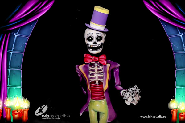 Illusion of a dancing skeleton in a purple suit, red bow tie, and top hat, created with body painting; the skeleton holds playing cards in its hand.