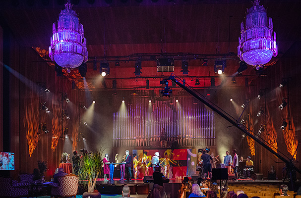 Bühnenszene beim World Bodypainting Festival 2021 mit farbenfroh bemalten Künstlern, großen Kronleuchtern und stimmungsvollem Lichtdesign.